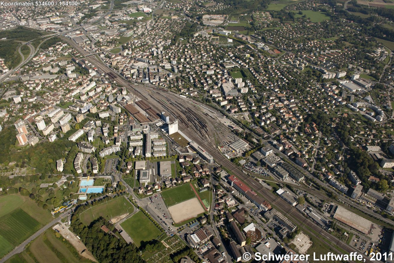 Lausanne Renens; Güterbahnhof (Blickrichtung N; Position 2'534'629.70, 1'154'241.52 ). Autobahn A1 links oben im Bild. Westlich des Bahnhofs: 'Le Censuy' mit Schwimmbad-Anlage. Unten im Bild: 'Stade du Censuy'. Östlich (rechts Mitte): Stadtteil Prilly.